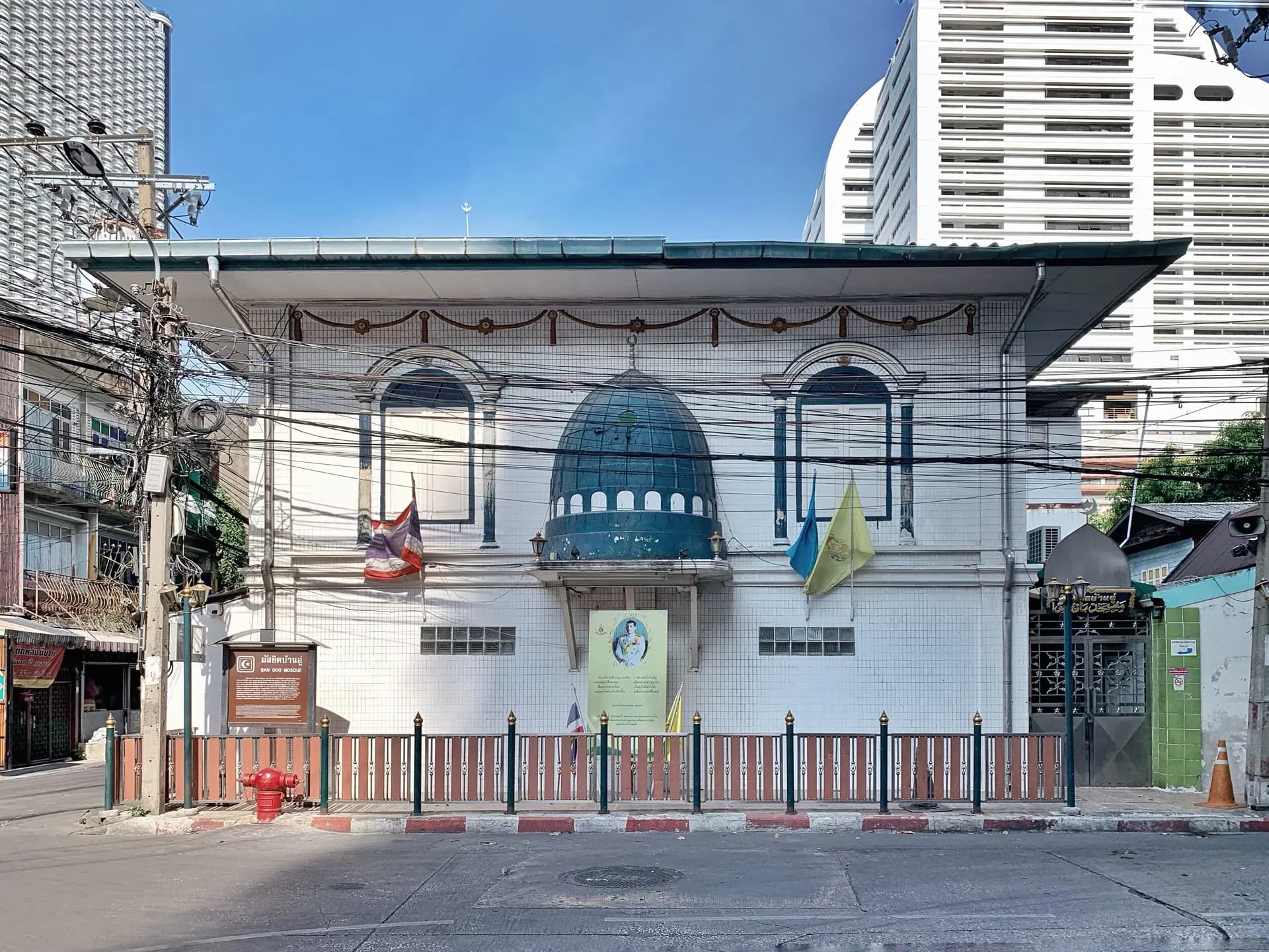 The white-tiled front of Ban U Mosque with its green dome and shuttered windows