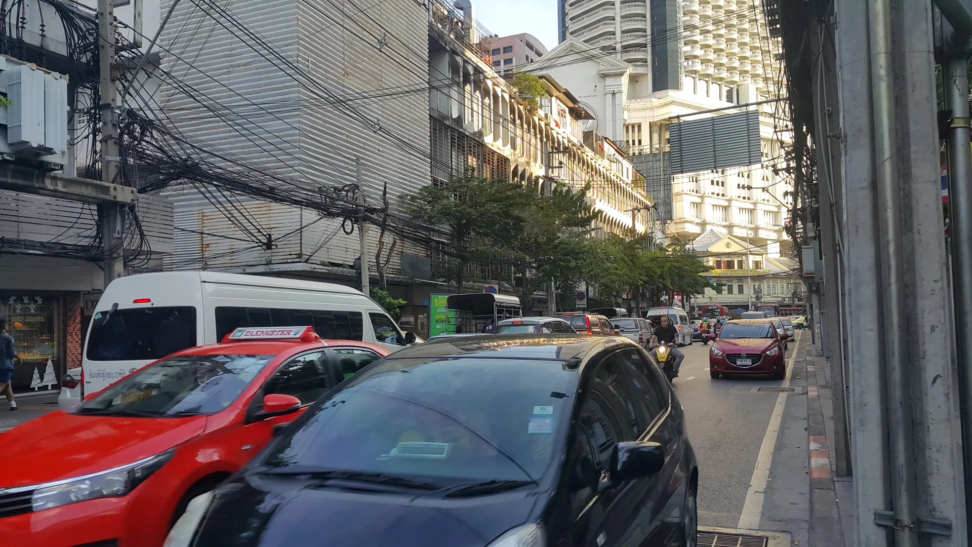 Charoen Krung Road with parked cars and older shophouses along the side