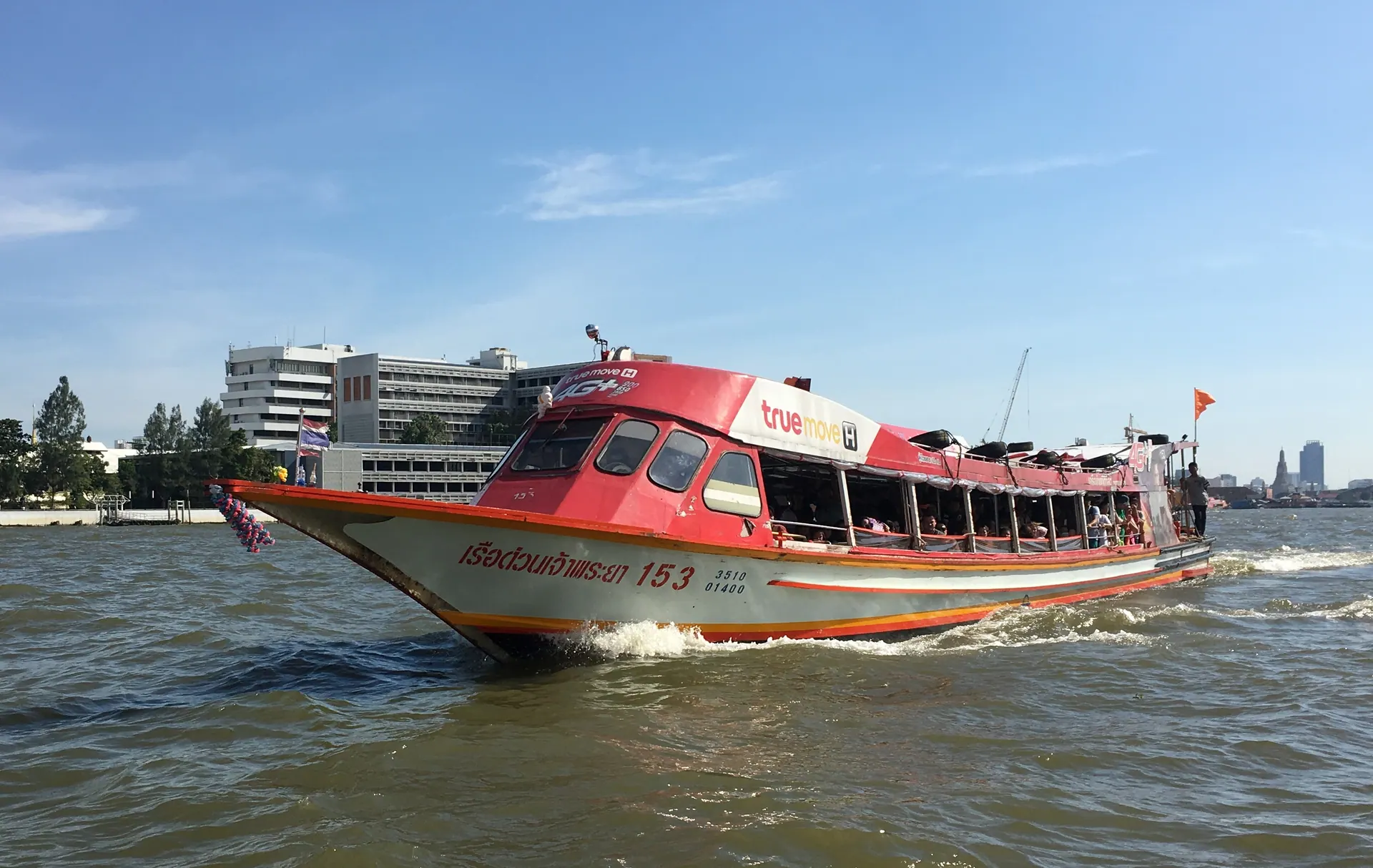 An orange-flag Chao Phraya Express Boat travelling on the river