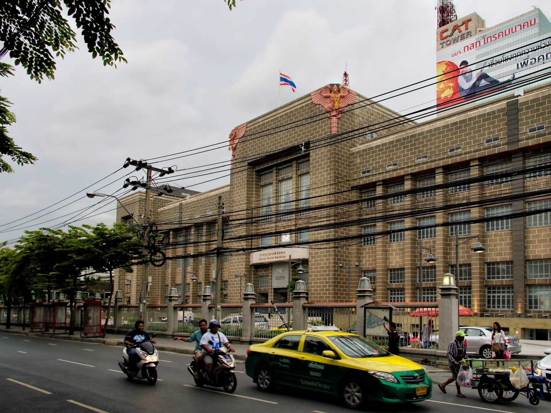 The Grand Postal Building on Charoen Krung Road with a taxi and motorbikes in front