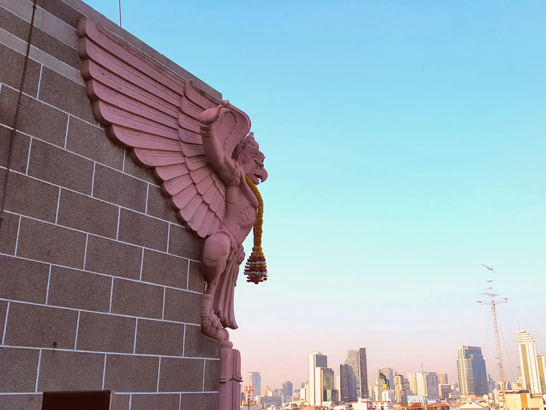 A carved garuda on the corner of the Grand Postal Building against the sky