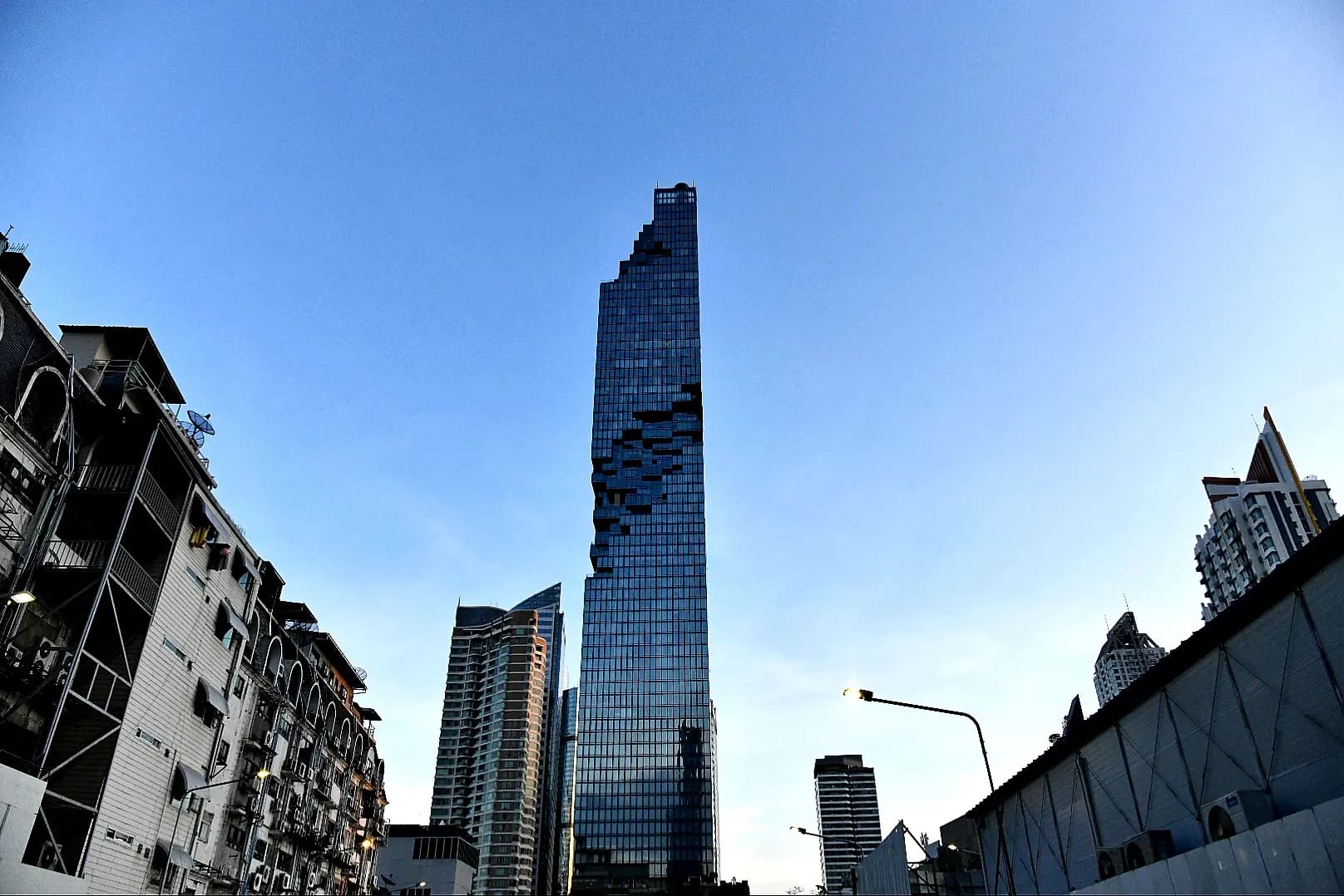 King Power Mahanakhon rising above older buildings against a blue sky