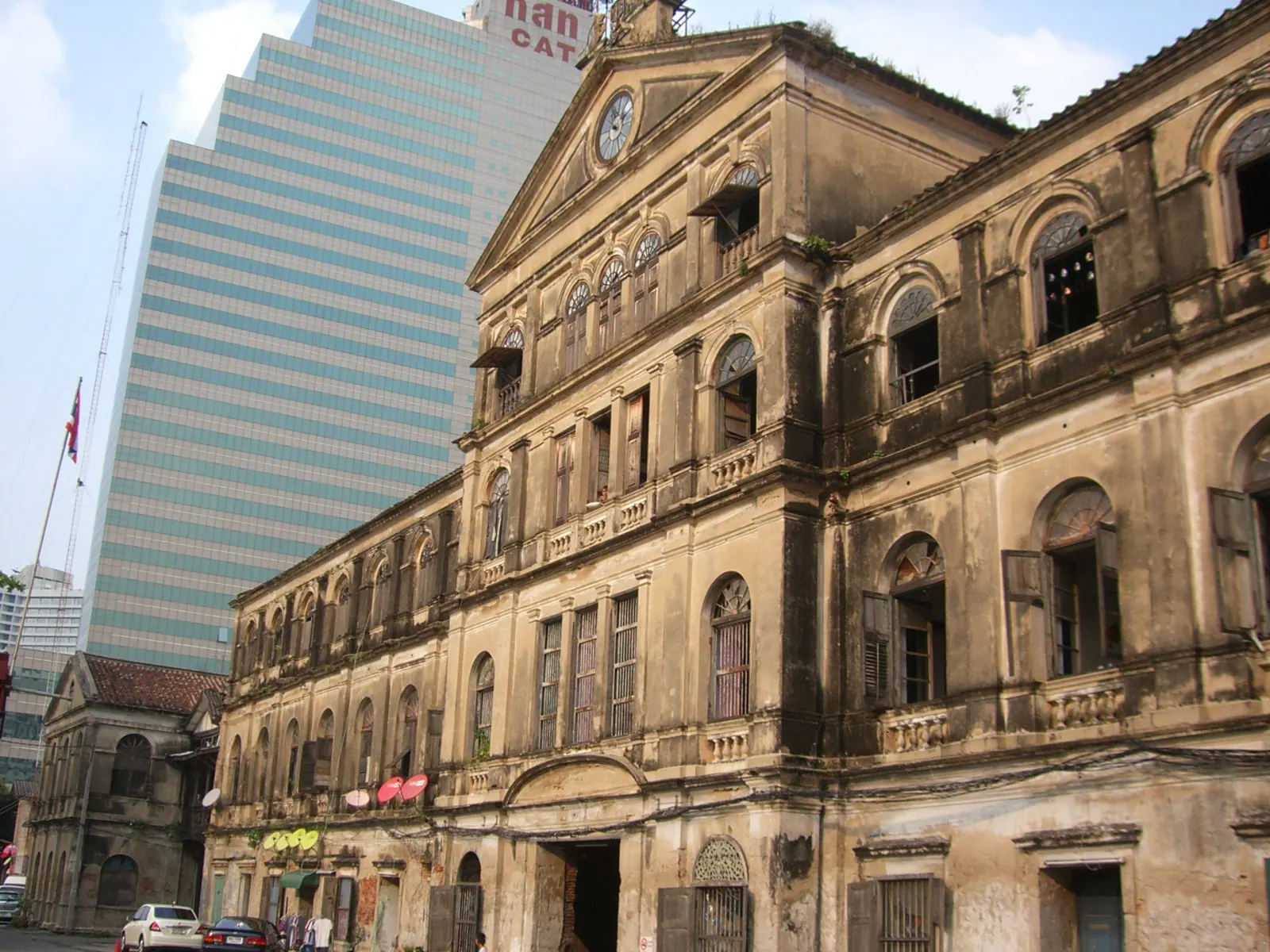 The weathered front of the Old Customs House in Bang Rak with a modern tower behind