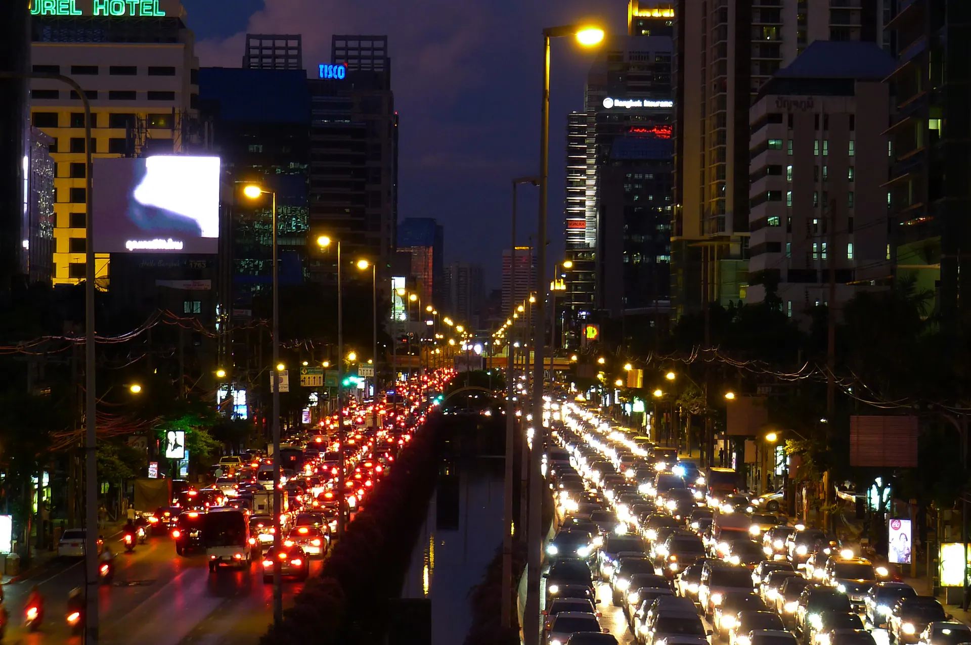 Sathon Road at night, filled with traffic and lit towers