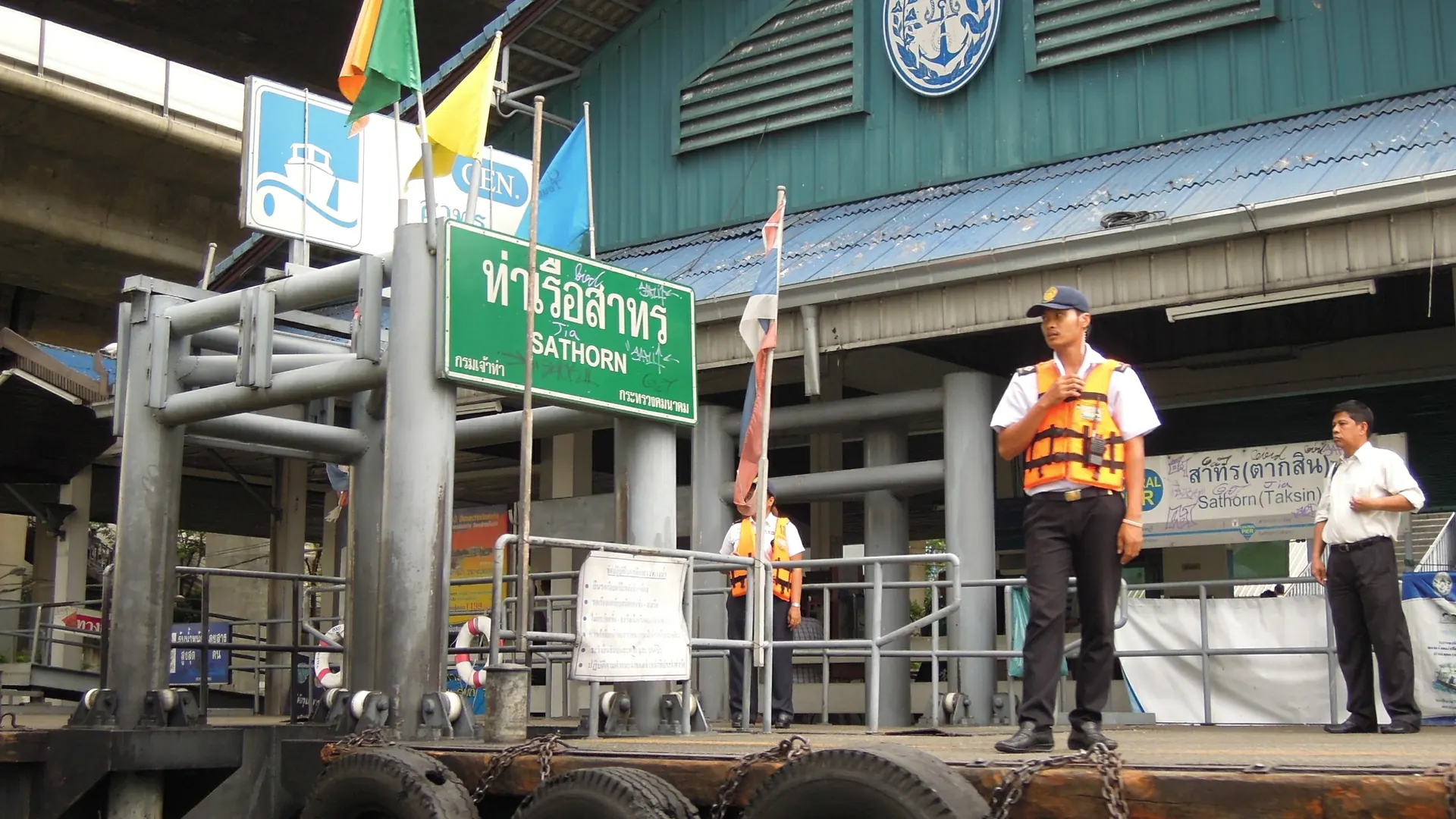 The Sathorn Pier landing on the Chao Phraya River, with the pier sign and staff