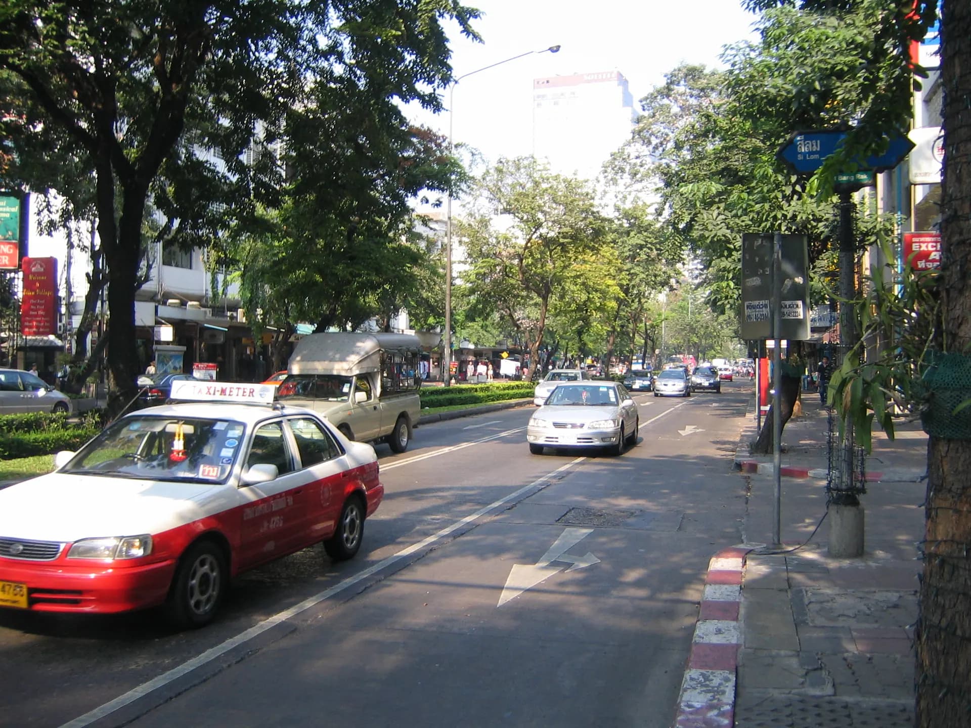 Silom Road with a tree-lined footpath and taxis