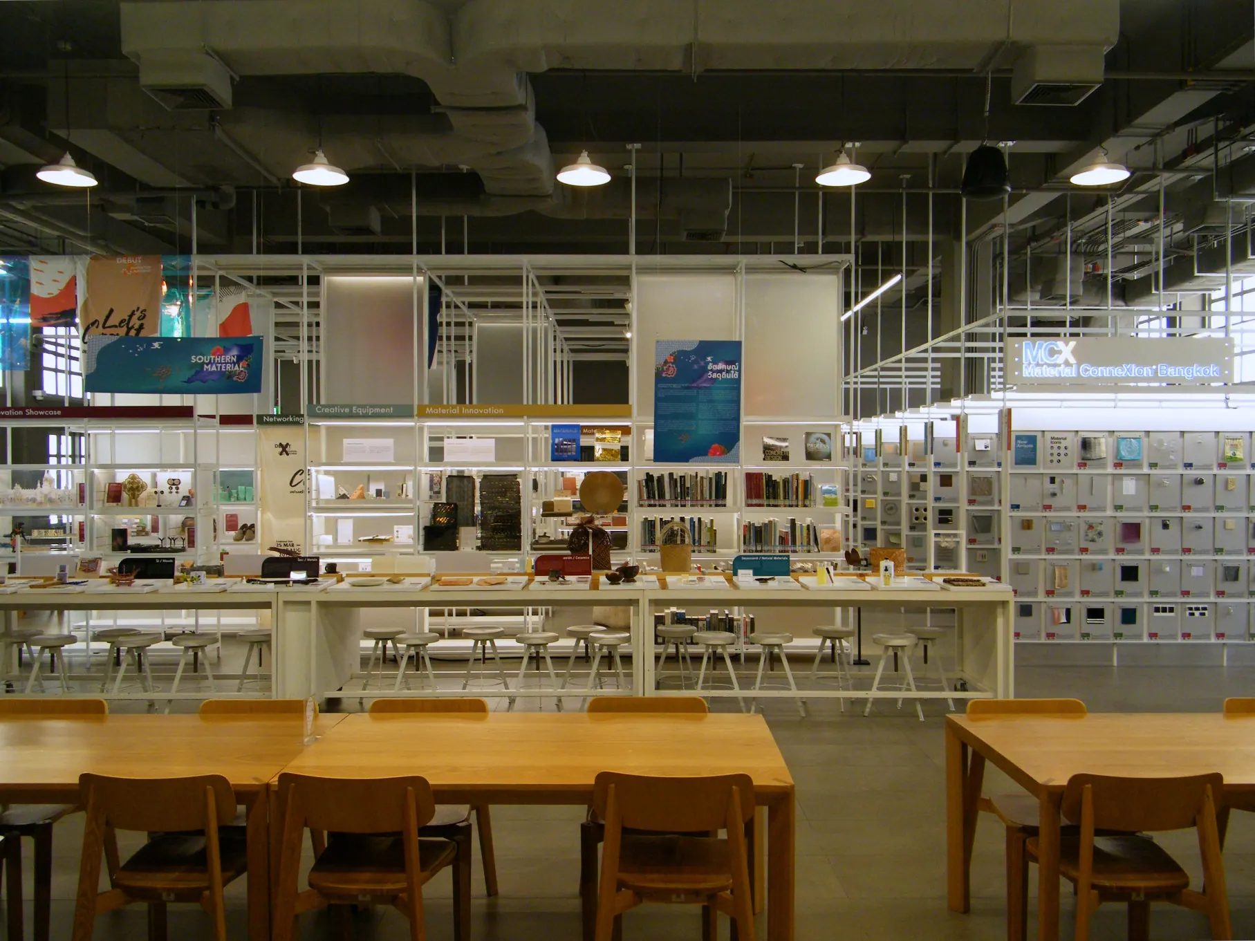 A bright design resource room with shelves and long tables at the Thailand Creative & Design Center